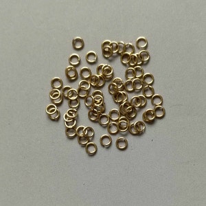 May include: A pile of gold jump rings, a type of jewellery finding used for connecting chains, cords, and other jewellery components.