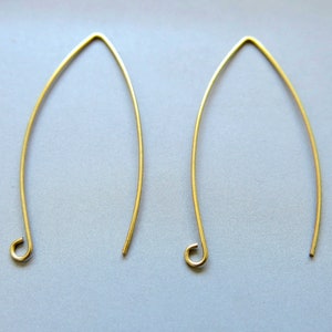 Pode incluir: Um par de ganchos para brincos dourados com um design simples e curvo. Os ganchos são de metal e têm um acabamento liso.