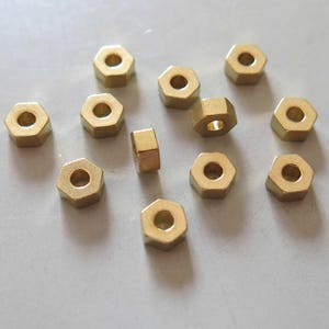 May include: A collection of 12 gold-coloured hexagonal nuts.