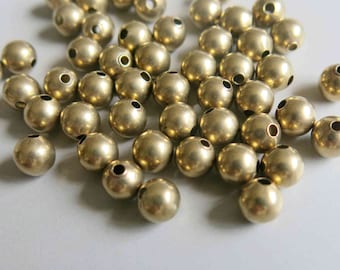 May include: A pile of gold-colored metal beads with a hole in the center of each bead.