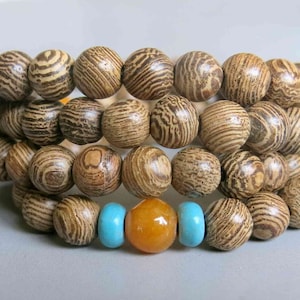May include: A wooden beaded bracelet with brown and white striped beads. The bracelet has a turquoise and orange bead accent.
