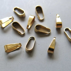 Op de afbeelding: Een groep van 10 gouden metalen hangerbedels, gebruikt om hangers aan kettingen of kettingen te bevestigen.