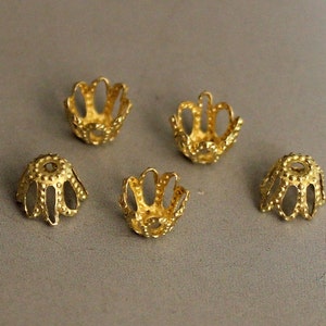 May include: Five gold-coloured metal bead caps with a scalloped edge and a textured surface.