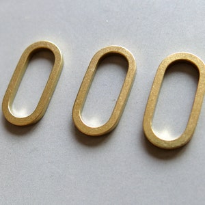 Puede incluir: Tres anillos ovalados de metal de color dorado. Los anillos son lisos y tienen un acabado brillante.