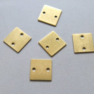 May include: Five gold-coloured metal squares with two holes each. The squares are arranged in a star shape.