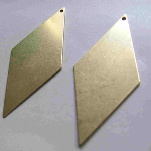 May include: Two gold-coloured metal diamond-shaped pendants with a hole at the top for hanging.