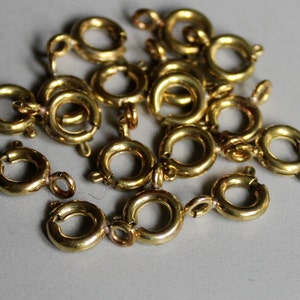 Puede incluir: Un montón de anillos de salto de metal dorado, también conocidos como anillos de conexión, utilizados para la fabricación de joyas.