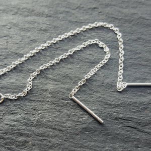 May include: Two silver chain earring extenders with a small silver bar at the end of each chain.