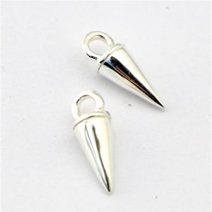 May include: Two silver-coloured, cone-shaped pendants with a loop at the top for attaching to a chain or other jewellery component. The pendants have a polished, reflective surface and a pointed tip. The background is plain white.