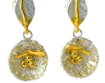 Puede incluir: Un par de pendientes de plata y oro con un delicado diseño de hoja y un colgante redondo texturizado en forma de nido con detalles dorados.