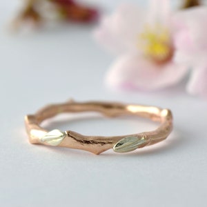Puede incluir: Un anillo de rama de oro rosa con dos hojas de oro blanco. El anillo es delicado y tiene un aspecto natural y org&aacute;nico.