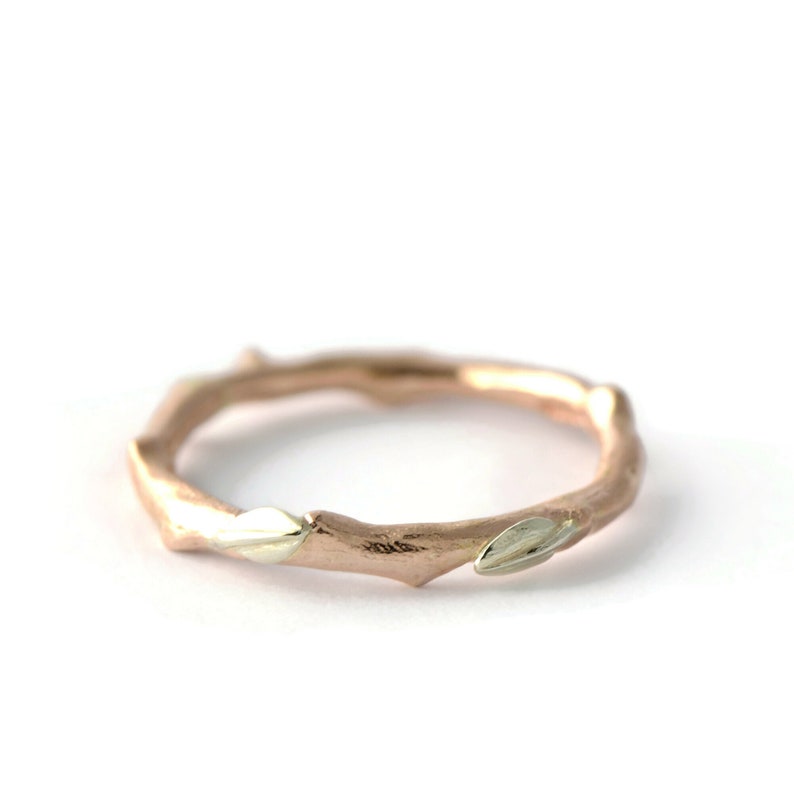 Puede incluir: Un anillo de oro rosa con un dise&ntilde;o de rama y peque&ntilde;as hojas de oro blanco.