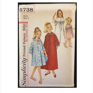 May include: Simplicity sewing pattern number 5738 for a child's nightgown. The pattern includes three different styles of nightgowns, one in red, one in blue, and one in white with pink trim. The pattern is for a child size 6.