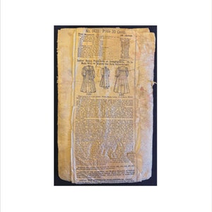 May include: A vintage sewing pattern for a woman's dress or lounging robe. The pattern is numbered 1428 and costs 30 pence. The pattern includes instructions and measurements for different sizes. The pattern is printed on a yellowed piece of paper with a faded image of the dress.