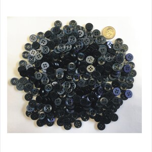 May include: A large pile of black buttons with four holes each. The buttons are about the size of a 10 pence coin.