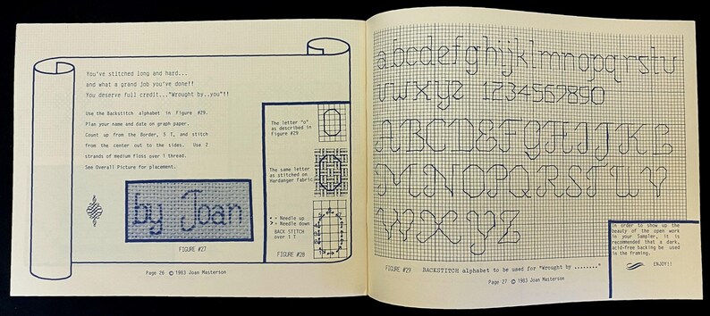 May include: Open book pages with cross-stitch instructions. One page features a scroll design with text and a stitched "by Joan" sample. The opposite page displays a grid with the alphabet and numbers for backstitch.