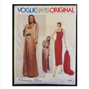 May include: Vintage Vogue Paris Original sewing pattern featuring Christian Dior designs. The pattern includes illustrations of elegant dresses and ensembles in shades of beige and red. The text "Vogue Paris Original" is displayed at the top.