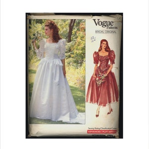 Peut inclure: Patron de couture original de mariage Vogue Patterns, numéro de patron 2399, difficulté avancée plus. Le patron montre deux femmes portant des robes de mariée. Une femme porte une robe blanche à manches bouffantes et une jupe ample. L'autre femme porte une robe rouge à manches bouffantes et une jupe ample.