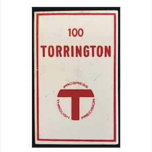 Può includere: Un cartello rettangolare con sfondo bianco e bordo rosso. Il cartello presenta il numero "100" sopra la parola "TORRINGTON" in lettere rosse. Sotto, un emblema circolare recita "PROGRESS THROUGH PRECISION" attorno a una forma a "T" rossa.