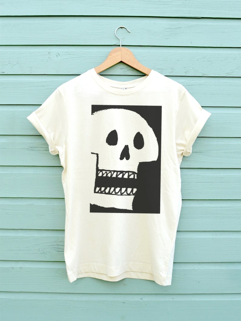 Op de afbeelding: Een wit T-shirt met een zwart-witte schedelprint op de voorkant. De schedel is gestileerd en heeft een grote, open mond.