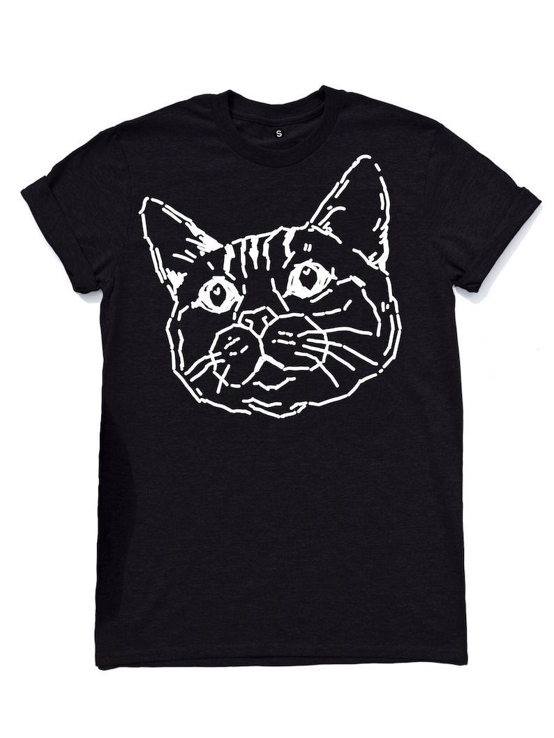 Puede incluir: Camiseta negra con un contorno blanco de la cara de un gato.