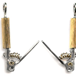May include: Two silver and gold metal clasps with a spring mechanism. Each clasp has a loop at the top and a small, round, silver knob at the bottom.