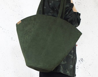May include: A large, dark green, suede tote bag with a wide, flat bottom and two long handles. The bag has a small, rectangular label on the front that says "Holbox".