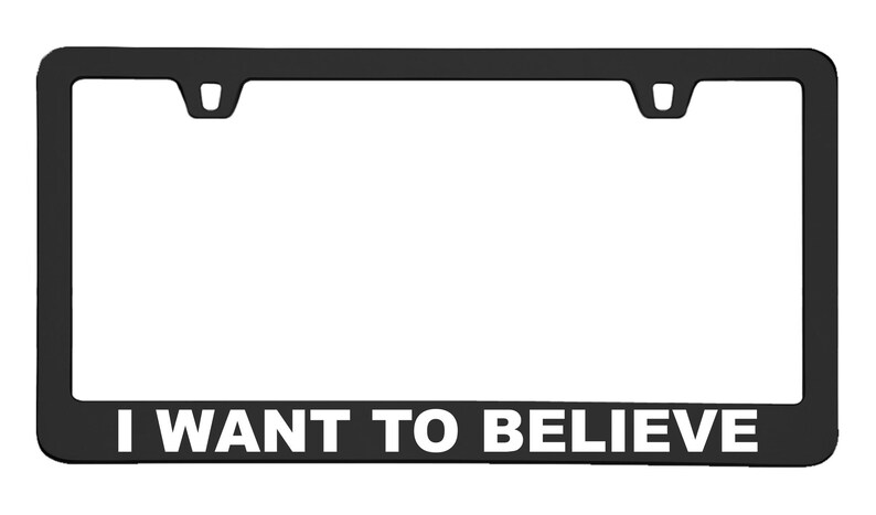 Puede incluir: Marco de matr&iacute;cula negro con texto blanco que dice "I WANT TO BELIEVE".