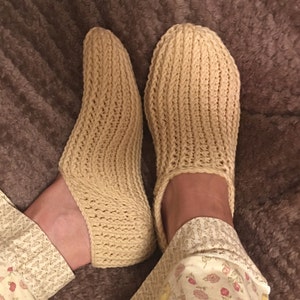 May include: A pair of beige knitted slipper socks with a simple stitch pattern.