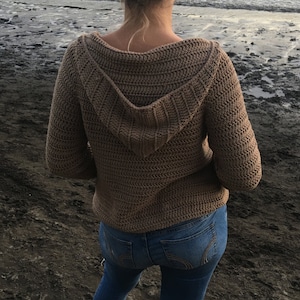 May include: A brown crocheted hooded sweater with long sleeves.