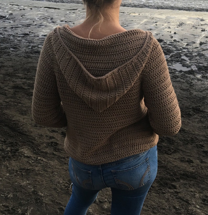 May include: A brown crocheted hooded sweater with long sleeves.
