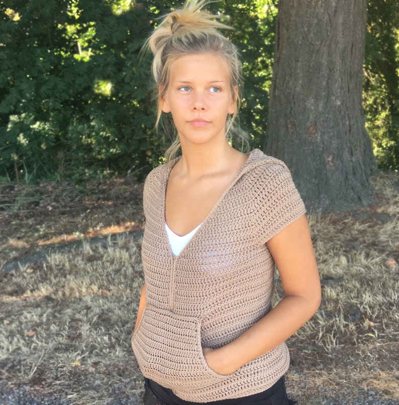 May include: A brown crocheted hooded top with short sleeves and a front pocket.