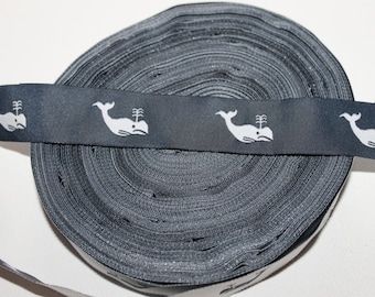 May include: A roll of black elastic trim with a white whale design. The trim is approximately 1 inch wide.