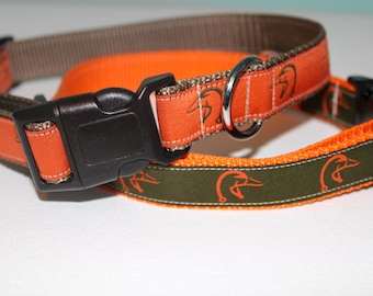 May include: Two dog collars with orange and green fabric. The collars have a repeating pattern of duck heads. One collar has a brown outer layer and the other has a black outer layer.