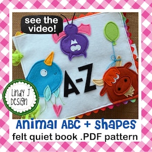 May include: A felt quiet book for children featuring animal shapes and letters from A to Z. The book is white with colorful felt appliques of a blue bird, a purple bat, a red cow, and the letters A-Z. The text "see the video!" and "Animal ABC + shapes felt quiet book .PDF pattern" is also visible.