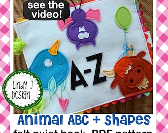Puede incluir: Un libro silencioso de fieltro para niños con formas de animales y letras de la A a la Z. El libro es blanco con aplicaciones de fieltro de colores de un pájaro azul, un murciélago morado, una vaca roja y las letras A-Z. El texto "¡ver el video!" y "Animal ABC + shapes felt quiet book .PDF pattern" también es visible.