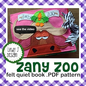Può includere: Una copertina per libro sensoriale in feltro rosa con un muso di bufalo marrone dalle grandi corna, un uccellino verde e la scritta Zany Zoo. Un nastro con stampa zebrata bianca e nera è fissato sul lato. Il testo Lindy J Design e see the video sono visibili.