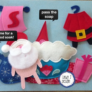 Op de afbeelding: Een vilt speelset met een kerstmanfiguur, een badkuip, een stuk zeep, een cadeau en een bord met de tekst "time for a good soak!"  De set is ontworpen voor kinderen om mee te spelen en te leren over badtijd.