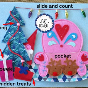 Op de afbeelding: Een vilten speelmat met een roze zak, een blauw-groene kerstboom, een rood-wit cadeau en een rood touwtje met lampjes. De tekst "slide and count" en "Lindy J Design" staan op de mat.
