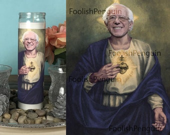May include: A white candle with a printed image of a man with a beard and glasses. The image is of a man in a blue robe with a heart on his chest. The text "FoolishPenguin" appears on the image.