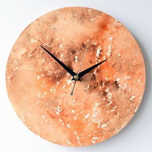 Puede incluir: Un reloj redondo de acuarela naranja y marr&oacute;n con manecillas negras.