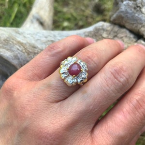 May include: A silver ring with a gold flower design and a pink gemstone in the center.