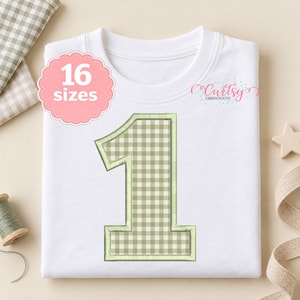 May include: A white t-shirt featuring a large number one applique with a light green and white gingham pattern. The design includes a light green stitched border. A pink scalloped badge displays the text 16 sizes, and the logo Curtsy Embroidery is visible.