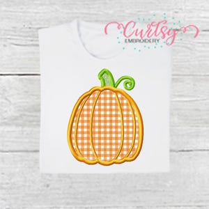 May include: White t-shirt featuring an embroidered pumpkin design. The pumpkin has an orange and white gingham pattern with a gold outline, green stem, and the text "Curtsy Embroidery".