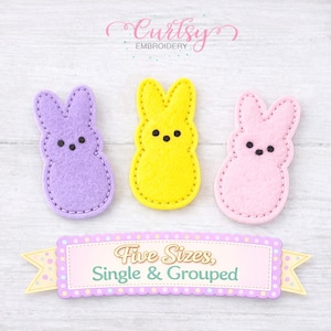 May include: Three felt bunny shapes in purple, yellow, and pink, each with black dot eyes and a stitched outline. The image includes text that reads "Five Sizes, Single & Grouped" in a banner below the bunnies. The word "Embroidery" is also visible.