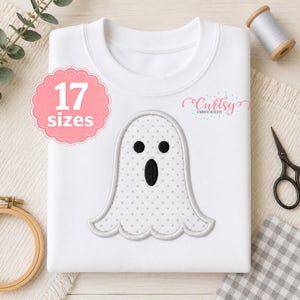 May include: A white sweatshirt featuring a central embroidered ghost design with a grey polka dot pattern, black eyes, and a black mouth. A pink scalloped badge displays the text 17 sizes, and the logo Curtsy Embroidery is visible.