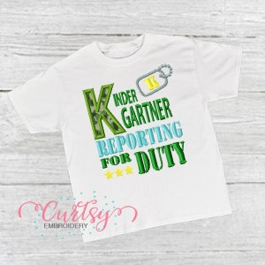 Peut inclure: T-shirt blanc avec la lettre K en camouflage vert, le texte vert "Kinder Gartner Reporting for Duty" et trois étoiles jaunes.