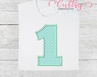 Puede incluir: Camiseta blanca con un gran número "1" bordado en color verde azulado claro con lunares blancos. El número está delineado en un verde azulado más oscuro. La palabra "Embroidery" está escrita en rosa en cursiva.
