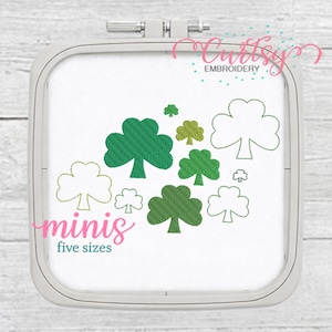 Puede incluir: Un bastidor de bordado con tela blanca con tréboles verdes de varios tamaños. La palabra "minis" en escritura rosa es visible, con "five sizes" debajo. El texto "Cursley EMBROIDERY" está en la esquina superior derecha.