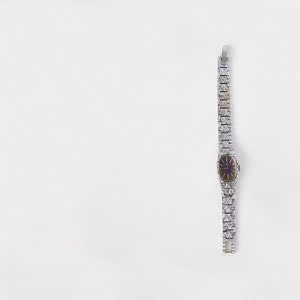 May include: A silver watch with a silver band and a dark blue face.